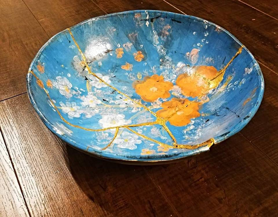 A blue pottery bowl with gold flowers and gold seams where it was repaired